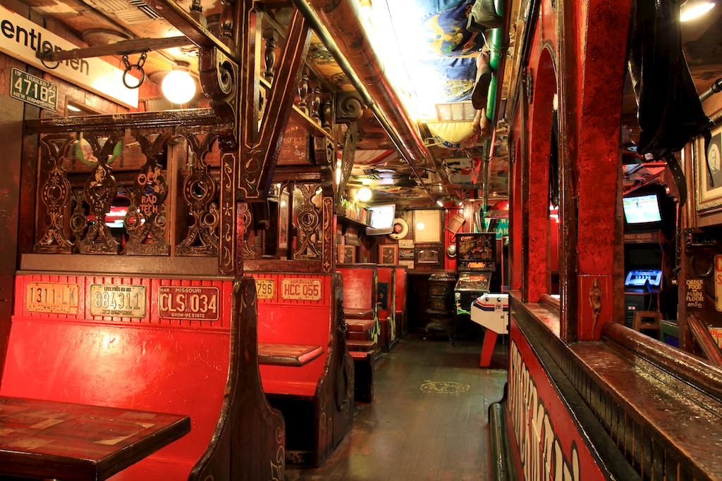 Image of the inside of Fanny Ann's Saloon. Decor seems to be modeled after a train coach. Each booth is bright red with license vintage license plates decorating the seats.